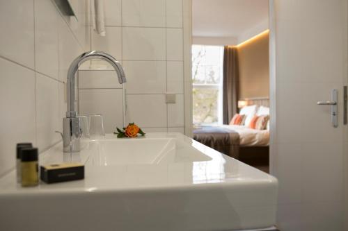 a white kitchen with a sink and a bedroom at Landgoed Hotel & Restaurant Carelshaven in Delden
