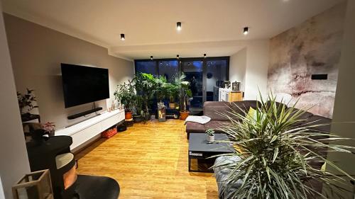 a living room with potted plants and a flat screen tv at Marleens Ferienhaus am See in Schwerin