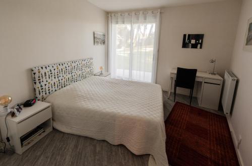 une chambre avec un lit, un bureau et une fenêtre dans l'établissement Le Cikhara, à La Baule