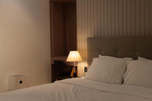 a bedroom with a bed with a lamp and a chair at The Azure Villa W Large Pool And Outdoor Garden in Bùi Tiếng
