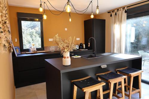 une cuisine avec un évier et un comptoir avec des tabourets dans l'établissement Casa Corsa - T4 Neuf de Standing avec Terrasse Spacieuse, à Bonifacio