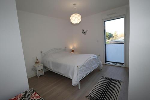 a white bedroom with a bed and a window at L'Aigue Marine by Tranquil at Home in Pornichet