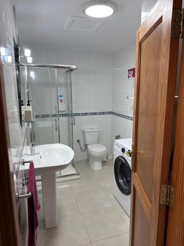un bagno con un lavandino del water e una lavatrice di Casa Lucia 2 a Cotillo
