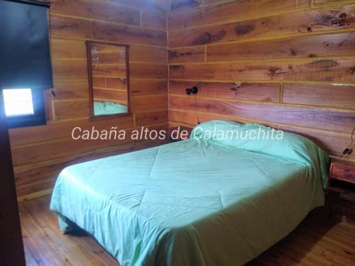 a bedroom in a log cabin with a bed at Cabaña Altos de Calamuchita in Santa Rosa de Calamuchita