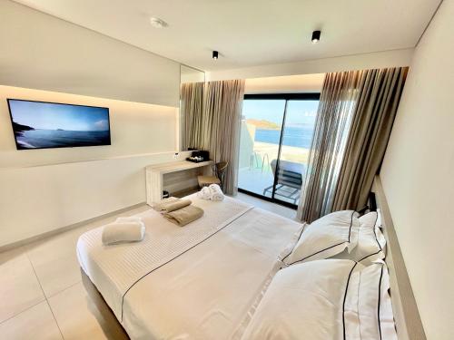 a bedroom with a large bed and a large window at Eleia Seafront Rooms & Villas in Petra