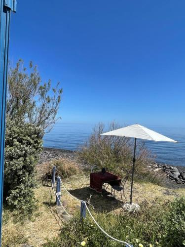 a table and an umbrella on the beach at Il Nido in Stromboli