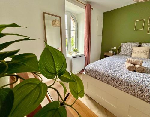 - une chambre verte avec un lit et une plante dans l'établissement La reine du faubourg, à Dijon