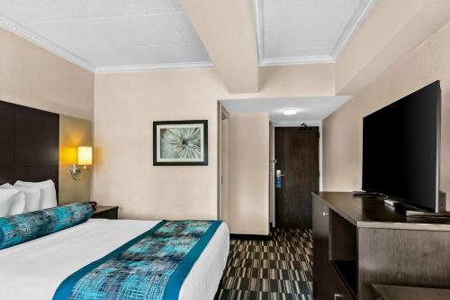 a hotel room with a bed and a flat screen tv at Best Western Downtown Sudbury in Sudbury