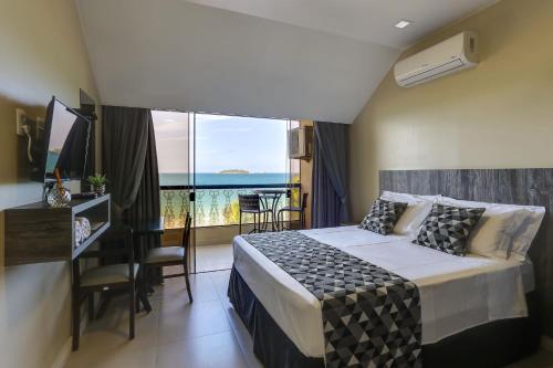 a bedroom with a bed and a desk and a balcony at Flat Pietra in Florianópolis