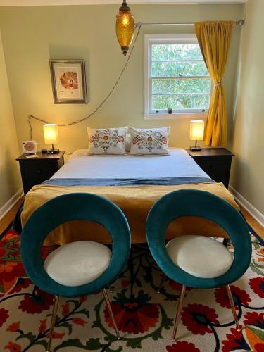 a bedroom with a bed and two blue chairs at Happy Haven w hottub, Gym, & hammocks in West AVL in Asheville