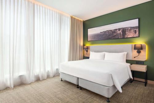 a bedroom with a white bed and a green wall at Radisson Hotel & Residence Riyadh Olaya in Riyadh