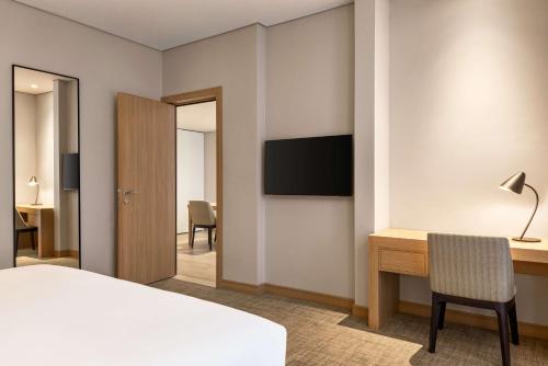 a bedroom with a bed and a desk and a television at Radisson Hotel & Residence Riyadh Olaya in Riyadh