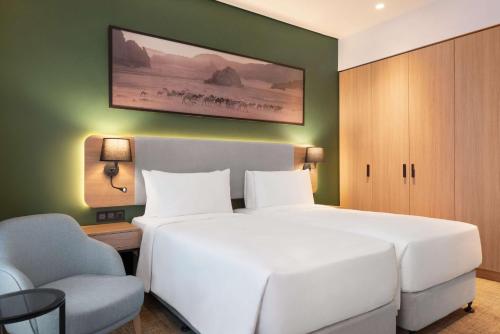 a bedroom with a large white bed and a chair at Radisson Hotel & Residence Riyadh Olaya in Riyadh
