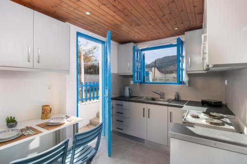 a kitchen with white cabinets and blue accents at Milos Sea House in Empourios