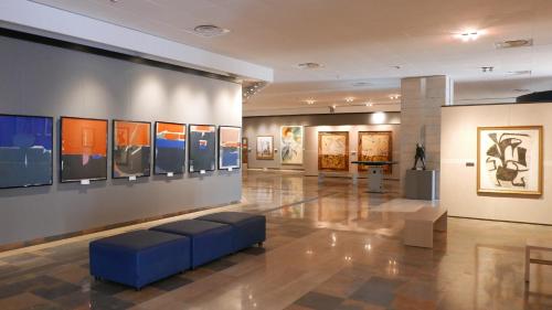 a museum with paintings on the wall and a blue couch at Three Rooms in Messina