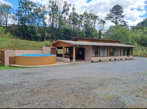 a house with a swimming pool in front of it at Sitio e Pousada Som das Águas in Barracão