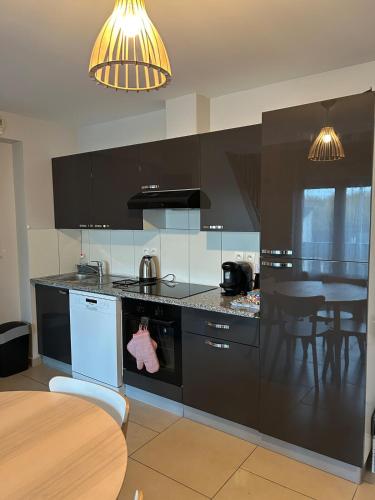 une cuisine avec des appareils en noir et blanc et une table dans l'établissement Appartement cosy idéalement situé, à Chelles