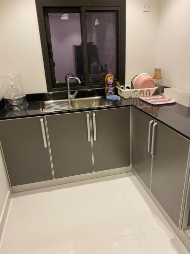a kitchen with grey cabinets and a sink at شقة فخمة مودرن in Jazīrat as Sāyah