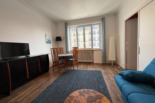 un salon avec un canapé bleu et une télévision dans l'établissement Charming T2 close to the train station - Caen, à Caen