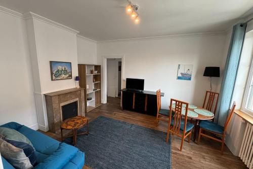 un salon avec un canapé bleu et une table dans l'établissement Charming T2 close to the train station - Caen, à Caen