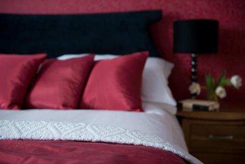 a bed with red and white pillows and a table with a lamp at The Claremont in Brighton & Hove