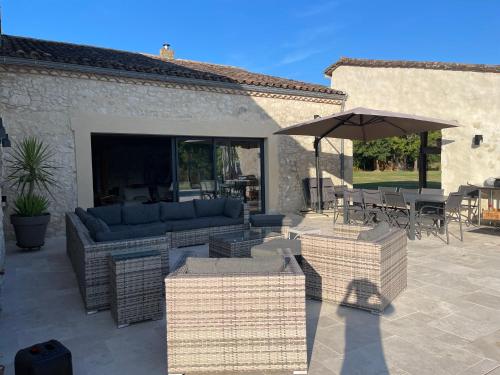 une terrasse avec un canapé et un parasol dans l'établissement Villa Fongrive, ferme Périgourdine haut de gamme, à Thénac
