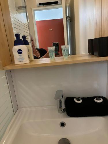 La salle de bains est pourvue d'un lavabo, d'un distributeur de savon et d'un miroir. dans l'établissement La Faviere T2 4pers RDC avec Terrasse, à Bormes-les-Mimosas