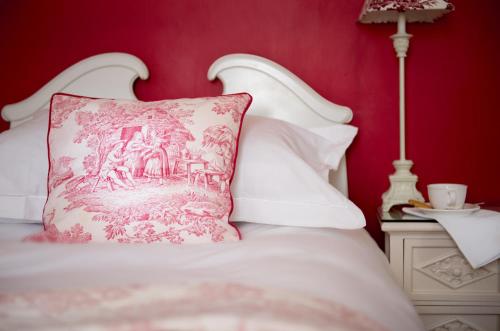 a red bedroom with a white bed with a pink pillow at The Claremont in Brighton & Hove