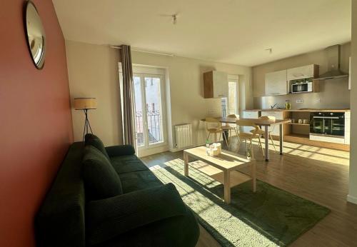 a living room with a green couch and a table at Le Premier Pas, départ du Saint Jacques in Le Puy en Velay