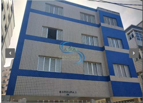 a tall blue and white building with windows at Vila Caiçara 80 metros da praia in Praia Grande