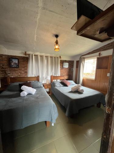 a bedroom with two beds and a window at La Misión Cabañas Chignahuapan in Chignahuapan