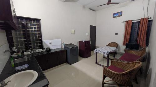 a bathroom with a sink and two chairs in it at Sinai Homestay in Trivandrum