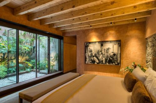 a bedroom with a large bed and large windows at Casa Tenue in Mexico City