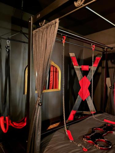 Cette chambre comprend un lit avec une croix et des rideaux. dans l'établissement Suite Interdite - Love Room - Les Suites Gaillardes, à Brive-la-Gaillarde