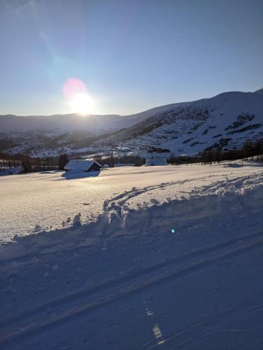 a snow covered field with the sun in the background at Hytte i Myrkdalen in Helgatun
