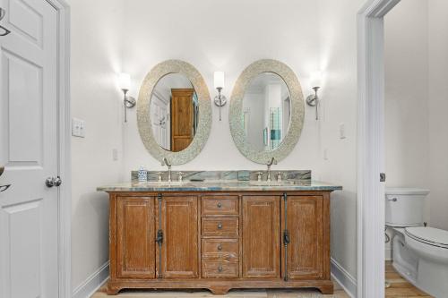 a bathroom with two mirrors above a wooden vanity at Blue Bayou in Gulf Highlands