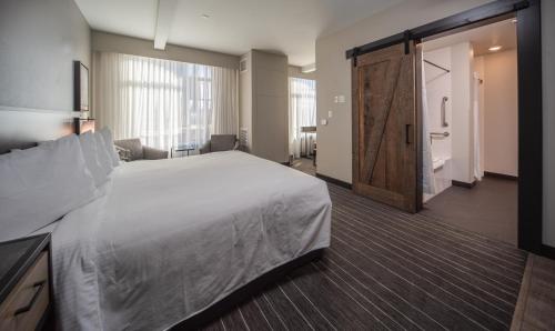 a hotel room with a large bed and a sliding door at Hotel Windrow Downtown Ellensburg in Ellensburg