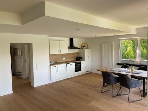 a kitchen with white cabinets and a table and chairs at #2 Ommi Kese Sansibar Apartment Panorama Balkon in Olpe