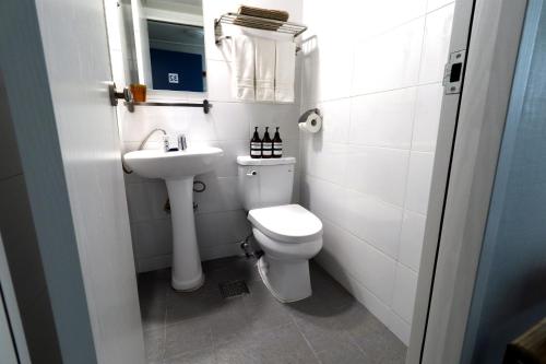 a white bathroom with a toilet and a sink at HAH Guesthouse in Seoul