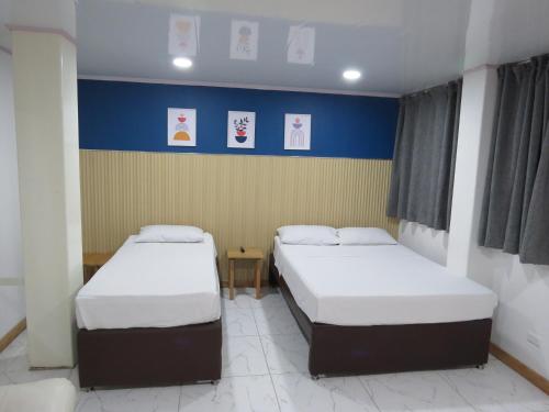 two beds in a room with blue and yellow walls at HOTEL A & A SANTA ALEJANDRIA in Medellín