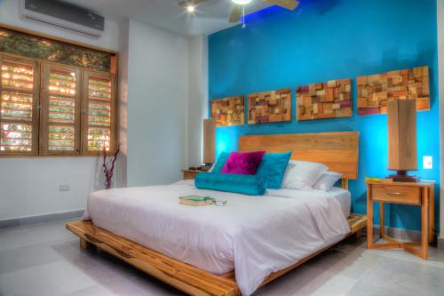 a bedroom with a large bed with a blue wall at Casa de Leda, a Kali Hotel in Santa Marta