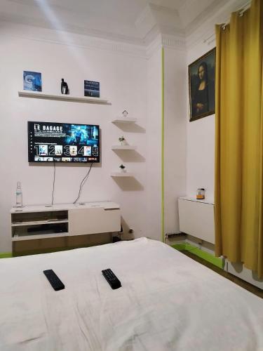 une chambre avec un lit et une télévision au mur dans l'établissement L'escale Azurienne, à Nice