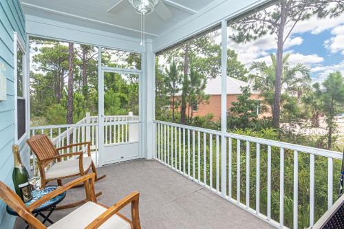 a screened porch with a rocking chair and a window at 7010 Rookery 3 Sea Shell Cottage New Build in bunks coming soon sleeps 10 in Gulf Shores