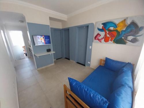a living room with a blue couch and a painting on the wall at Casa em condomínio no Centro de Bertioga com Ar condicionado in Bertioga