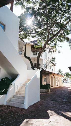 a white building with stairs and a tree at 2BR Beachfront Cadaques Caribe in Bayahibe