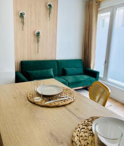 une table avec des assiettes, des verres et un canapé dans l'établissement MIDORI - Bel Appartement - Calais Centre, à Calais
