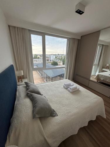 a bedroom with a large bed with a large window at Departamento céntrico con cochera y piscina Paz 341 in Tandil