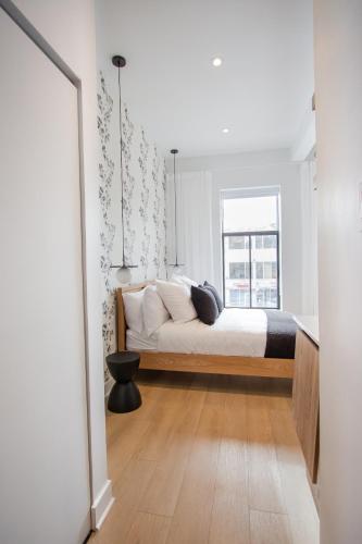 a bedroom with a bed with white sheets and a window at Studio #4 - Self Check-In - Plateau - St-Denis in Montreal