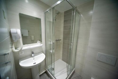 a bathroom with a glass shower and a sink at Logis Hôtel & Restaurant Au Lion d'Or in Burnhaupt-le-Haut