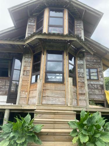 a wooden house with windows and plants in front of it at Chale Beija flor in Praia Grande